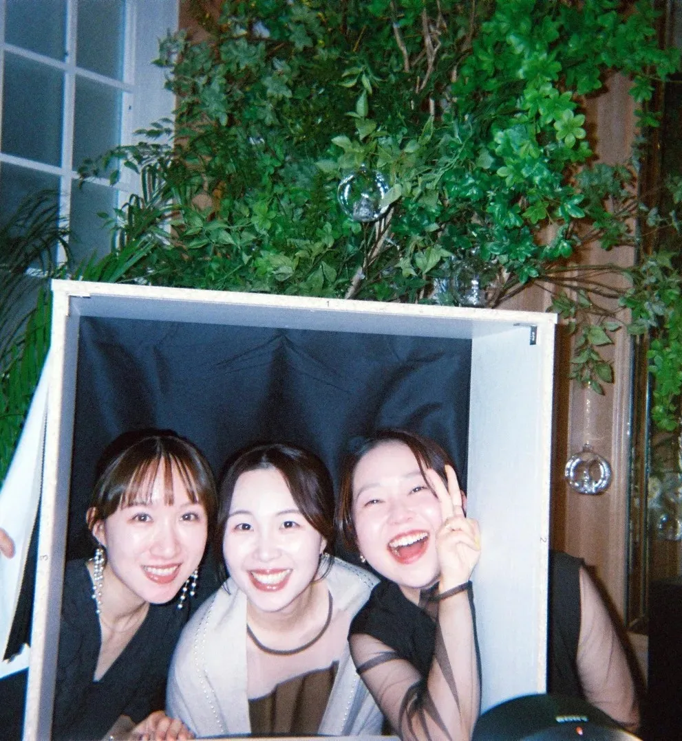 フォトブースから顔を出して笑う 3 人のゲスト