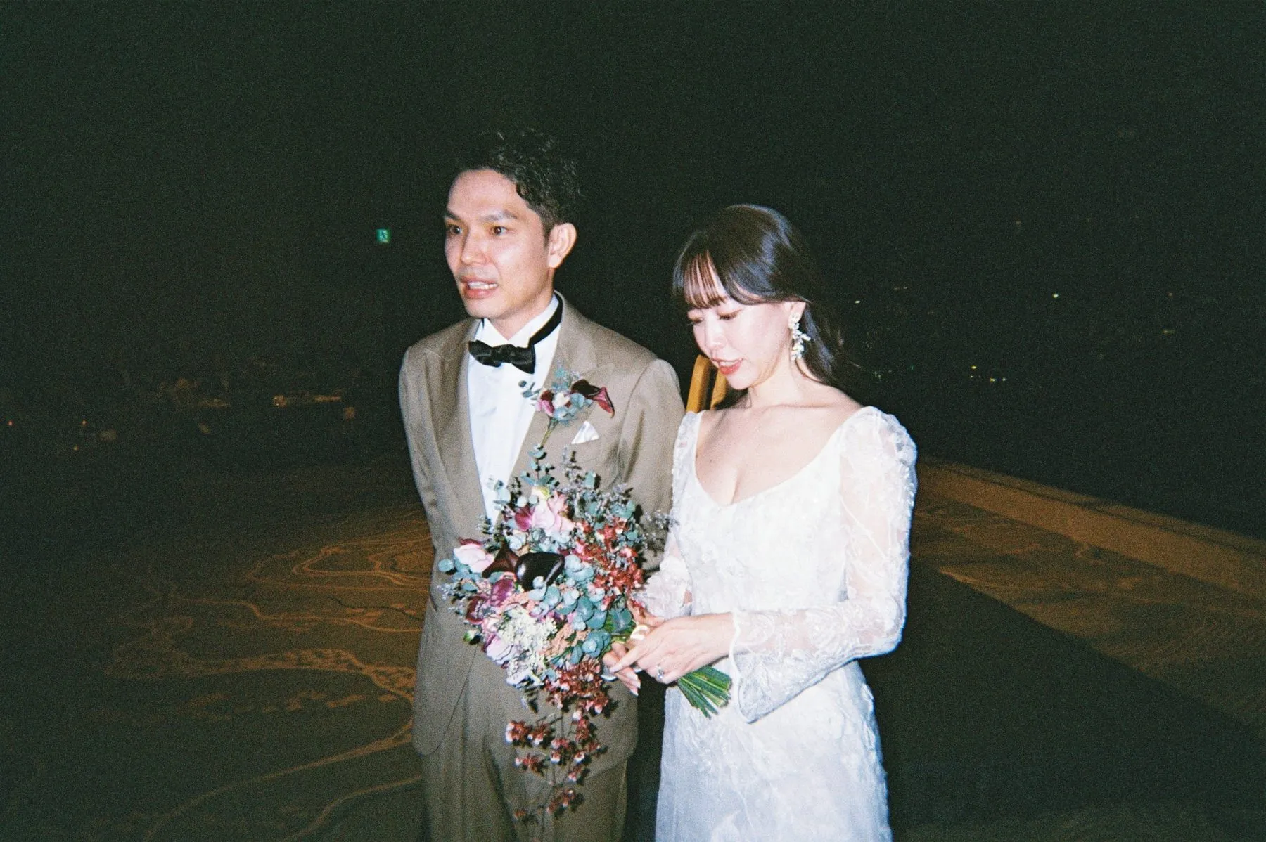 ブーケを手にした新婦と新郎。ゲストがフィルムカメラで撮影