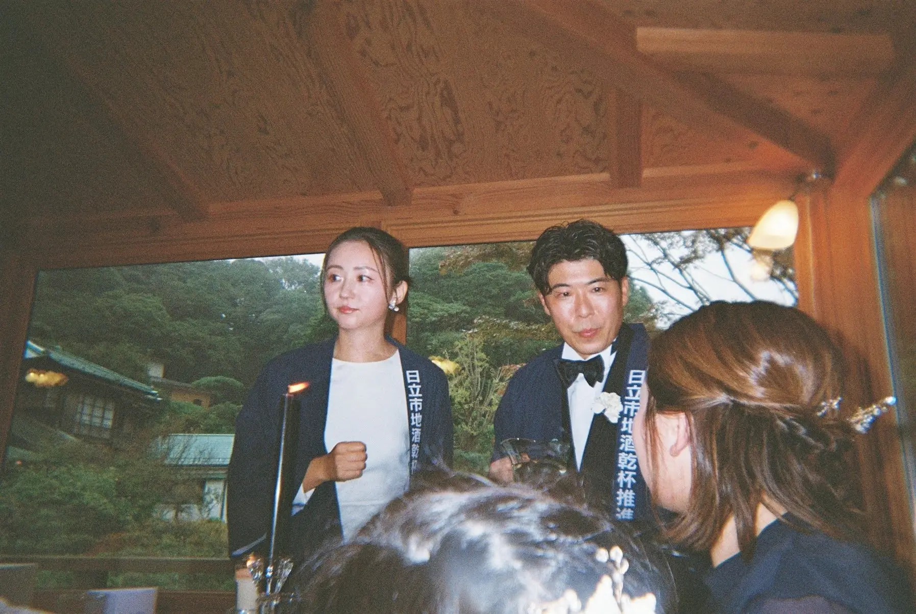 法被を羽織った新郎新婦と、手前で見守るゲストの後ろ姿