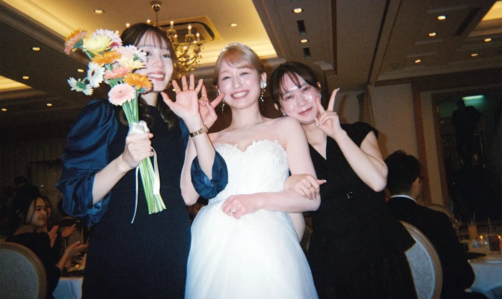 ブーケを持つ新婦とゲストがカメラに向かって笑う様子
