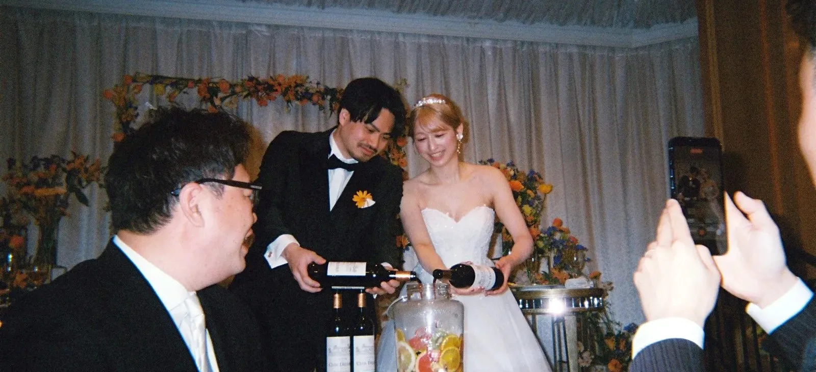 シャンパンタワーに注ぐ新郎新婦とスマートフォンで撮影するゲスト